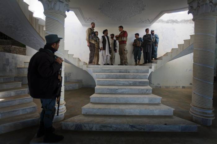 An Afghan Policeman stands guard while Chris Harich, (L) a US State Department Officer, and Kevin Melton (R) from USAID. Kate Holt.