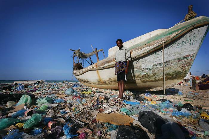 Haziz, an economic migrant from Ethiopia's Ogaden region, stands next to a boat. Kate Holt.