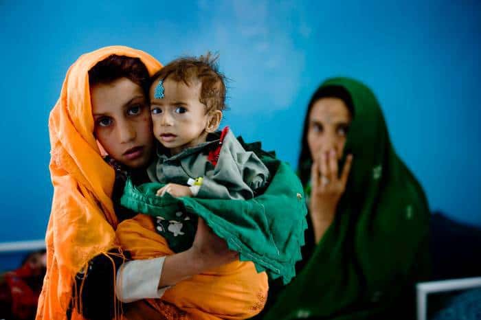 A young girl holds her nephew who is suffering from malnutrition at a therapeutic feeding centre. Kate Holt.