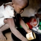 Neema Moshi washes up the dishes for her family after eating in the town of Makuyuni. Kate Holt.