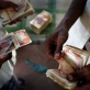 A Somali businessman counts out money for a passengers fare to Yemen. Kate Holt.