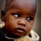 Simineti, who is two years old, is held by his mother on their homestead in Oldonyo. Kate Holt.