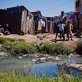 Children stand in front of a muddy stream that runs in front of their house in Antananarivo. Kate Holt.