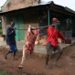 Two men carry meat in a traditional manner in the town of Mundri. Kate Holt.