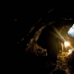 Miners walk along a damp tunnel with a kerosene lamp in an Emerald mine in Khenj. Kate Holt.
