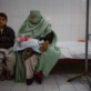 A woman, covered in a Burqa, holds her daughter while waiting to see a doctor. Kate Holt.