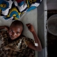 A young girl, suffering from cholera lies on her bed in a cholera treatment centre run by MSF. Kate Holt.