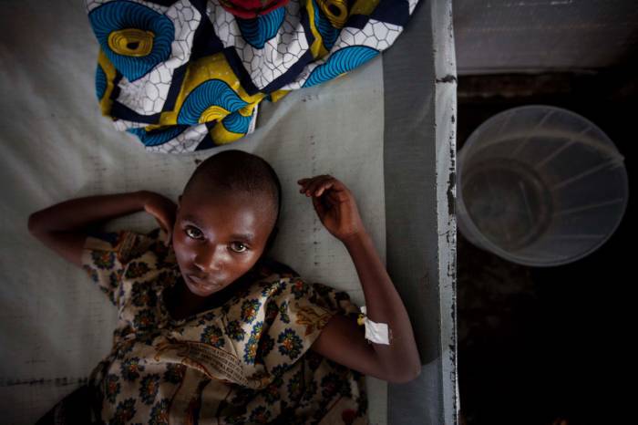A young girl, suffering from cholera lies on her bed in a cholera treatment centre run by MSF. Kate Holt.