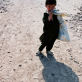 A young boy carries part of his family's food ration to their home in a refugee settlement. Kate Holt.