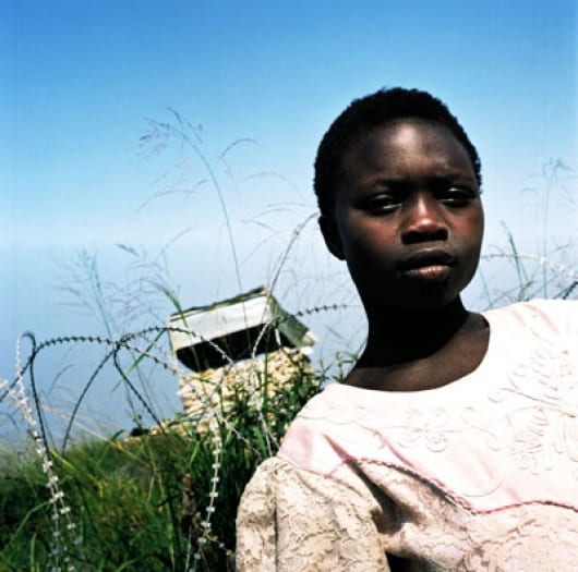 A young girl stands in front of a UN watch tower, situated 6 meters from her family's tent. Kate Holt.