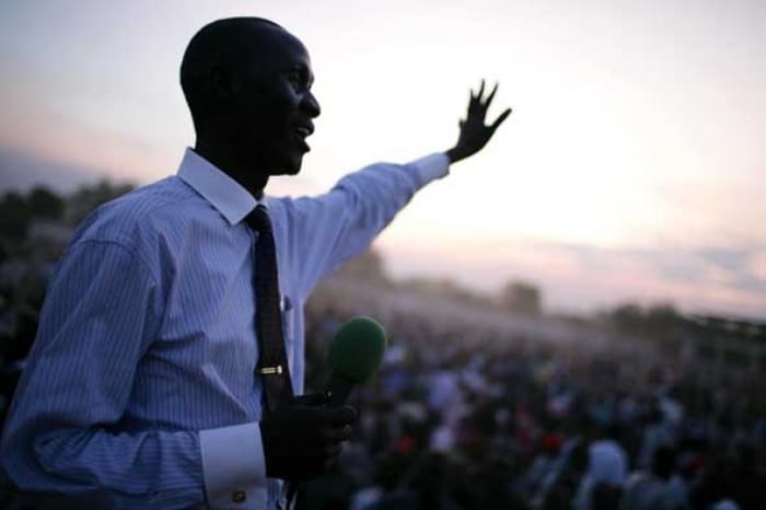 An evangelical Preacher speaks to a crowd of thousands of people in Juba town at sunset. Kate Holt.