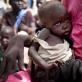 A woman holds her severely malnourished child while they wait to be registered to receive food aid. Kate Holt.